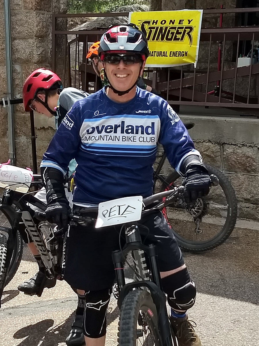 Pete in a blue cycling shirt with a Pete sign on his bike